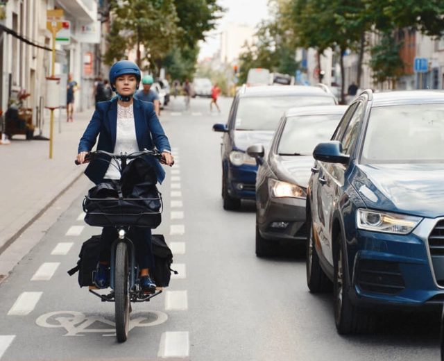 Femme à vélo sur une piste cyclable double une file de voitures