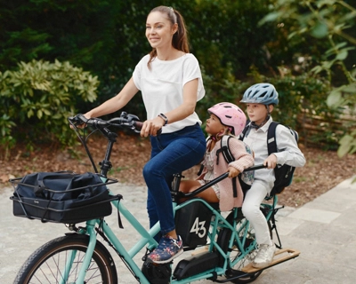 Femme transporte ses deux enfants sur un vélo triporteur