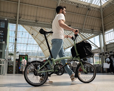 Homme pousse un vélo pliable et marche dans un hall de gare