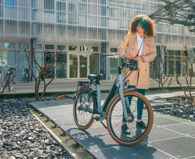 Femme salariée à vélo devant son lieu de travail