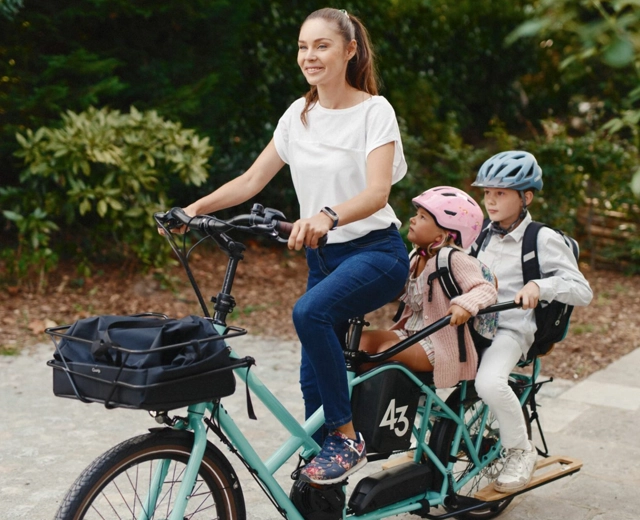 Femme à vélo à cargo avec deux enfants à l'arrière